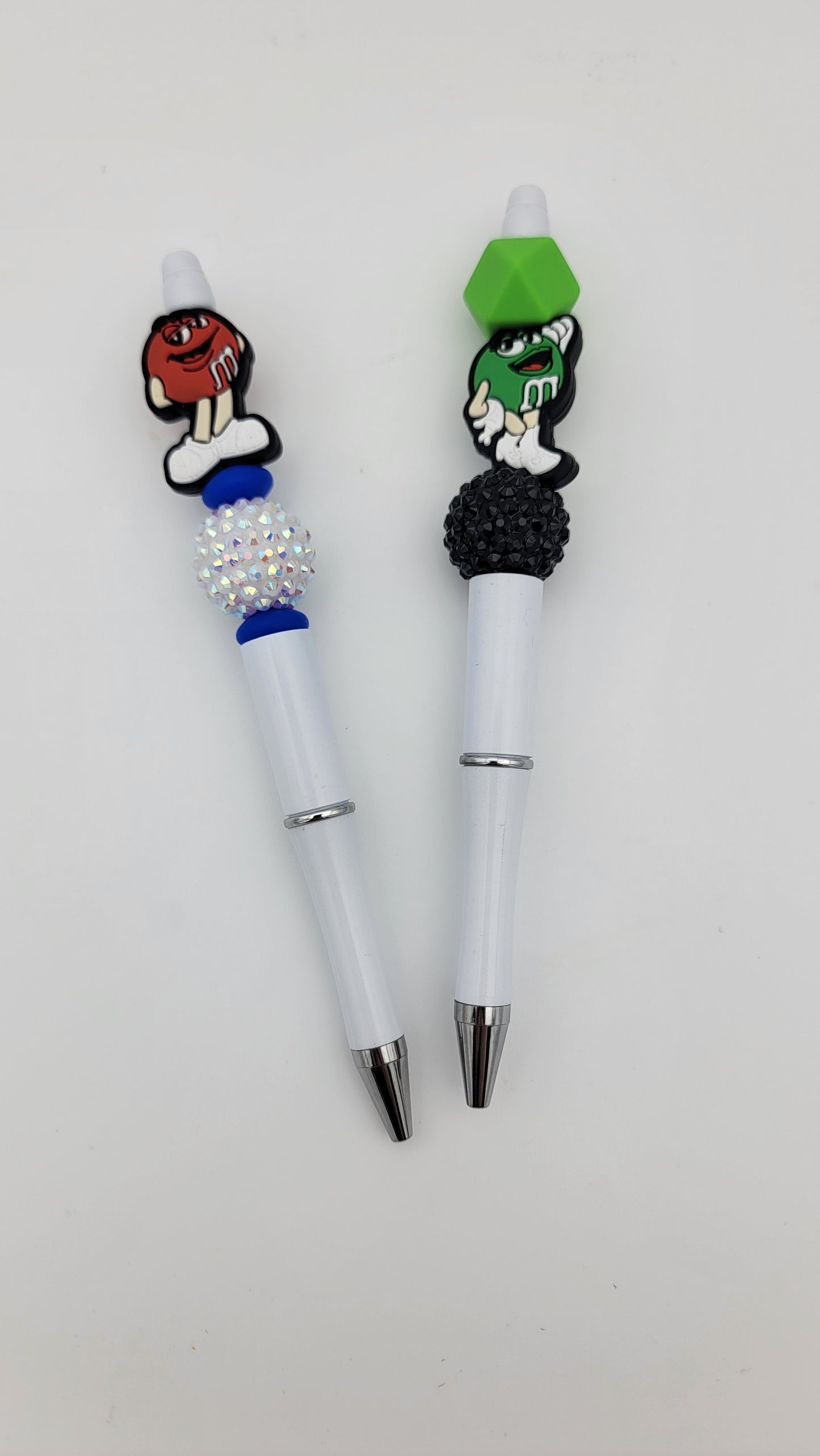 A set of novelty Beaded Pens-2 in 1 bag featuring decorative beads and colorful character toppers, including one red pen and one green pen, pictured on a plain white background.