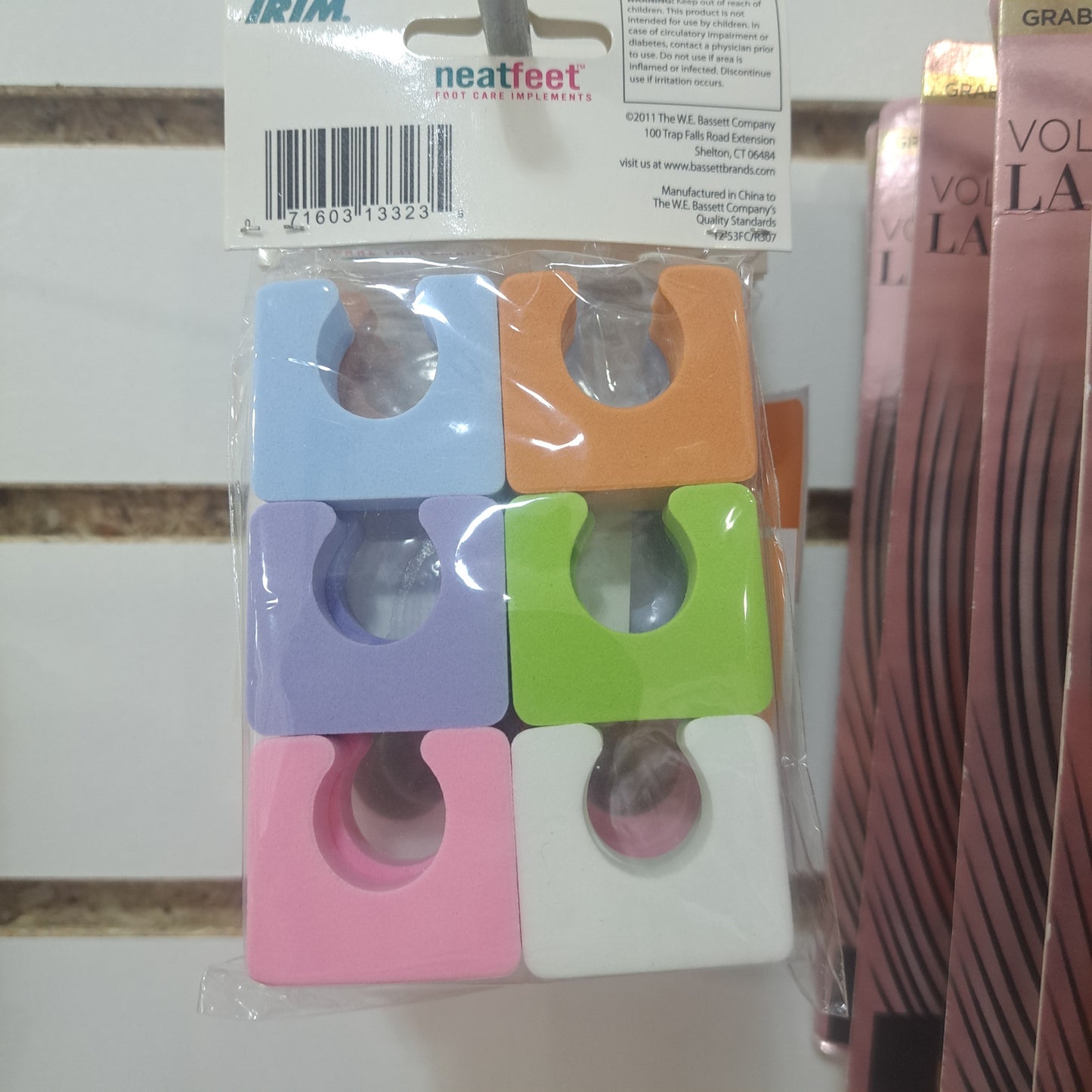 A package of six Trim Neat Feet Single Toe Separators in orange, green, blue, purple, white, and pink, displayed in a store.