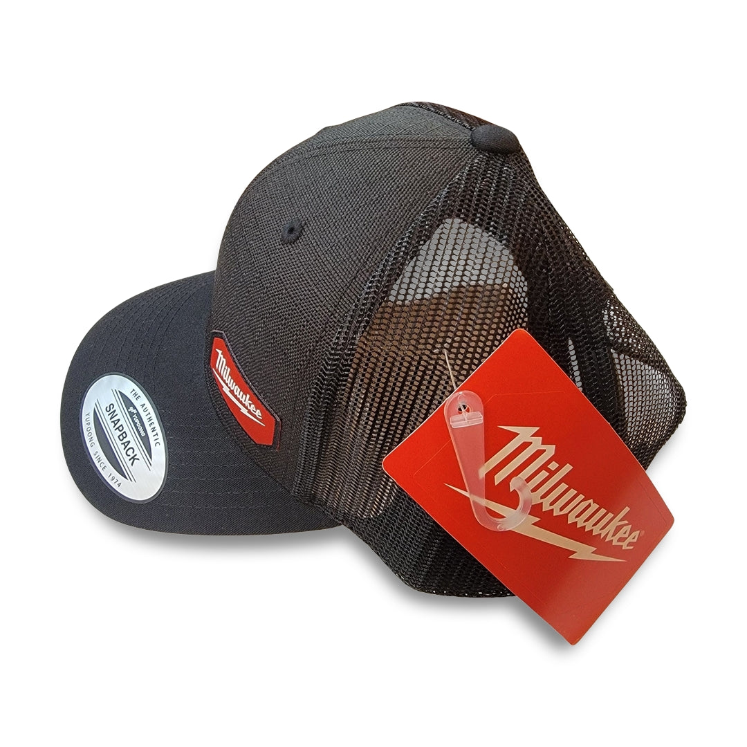 Milwaukee Black Snapback Hat featuring a red Milwaukee logo patch on the front and a red Milwaukee tag attached, positioned with the front facing left.