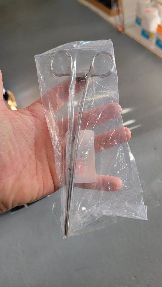 A hand holds a sealed plastic bag containing an 8" locking Hemo clamping tool.