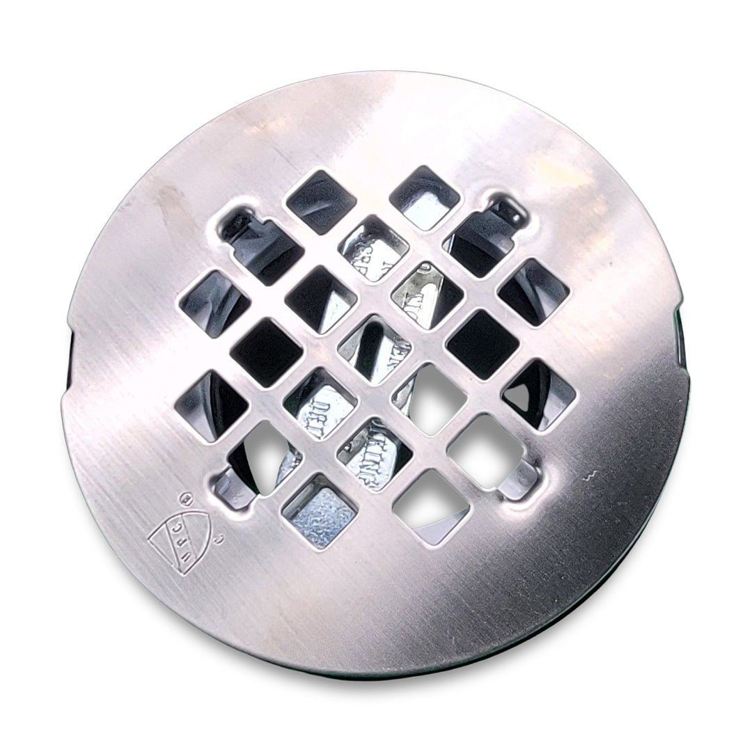 Close-up of the Westbrass d206p-20 PVC Compression shower drain featuring a round metal cover with a square grid pattern in the center.