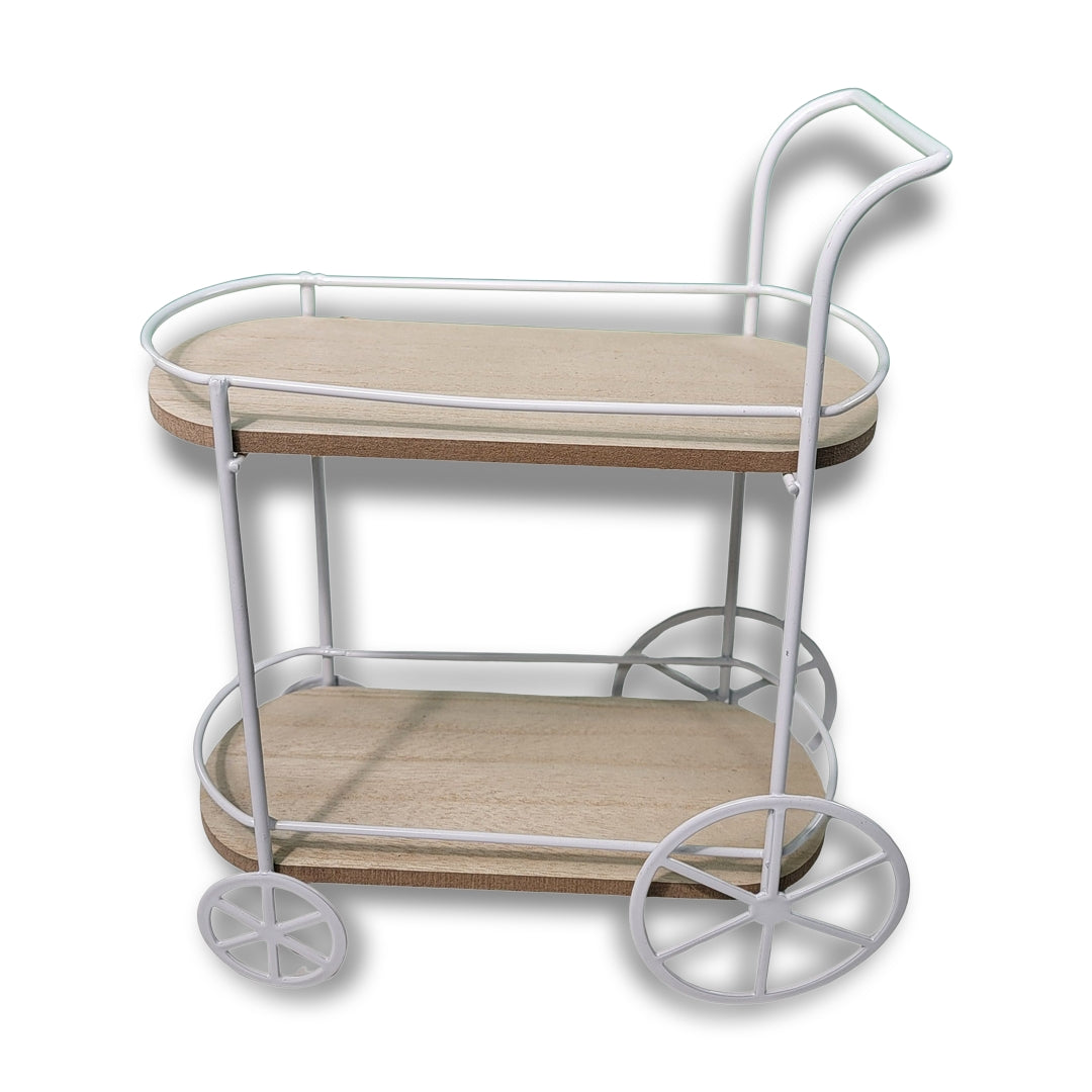 The Mini Bar Cart Novelty Décor features a two-tiered design with a white metal frame, wooden shelves, and two large wheels on one end.